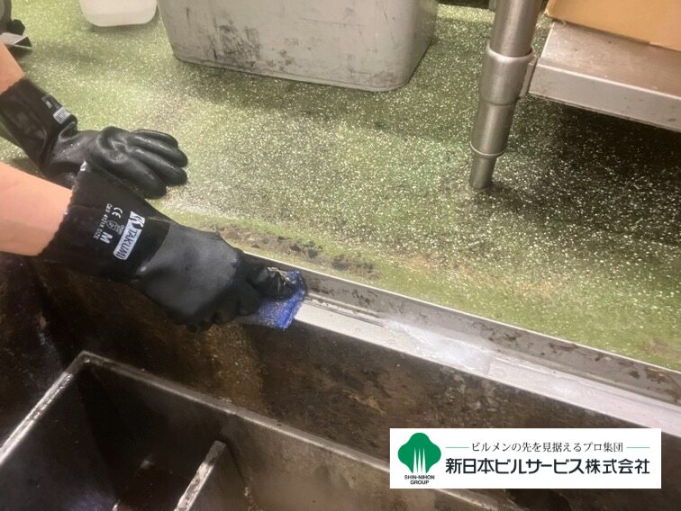 グリストラップのふちについた油脂を手作業で洗い流している清掃工程