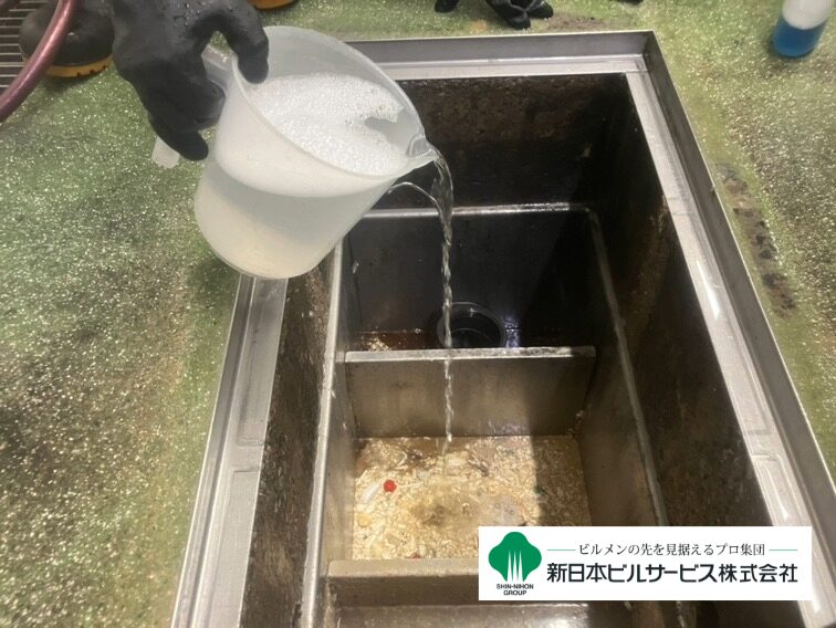 石鹸水化工法による清掃で、油脂を分解する専用薬剤をグリストラップ内に投入している写真