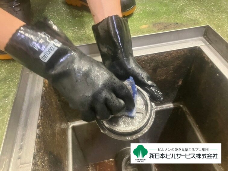 グリストラップのフタに付着した汚れや油脂を石鹸水で洗い流している清掃工程
