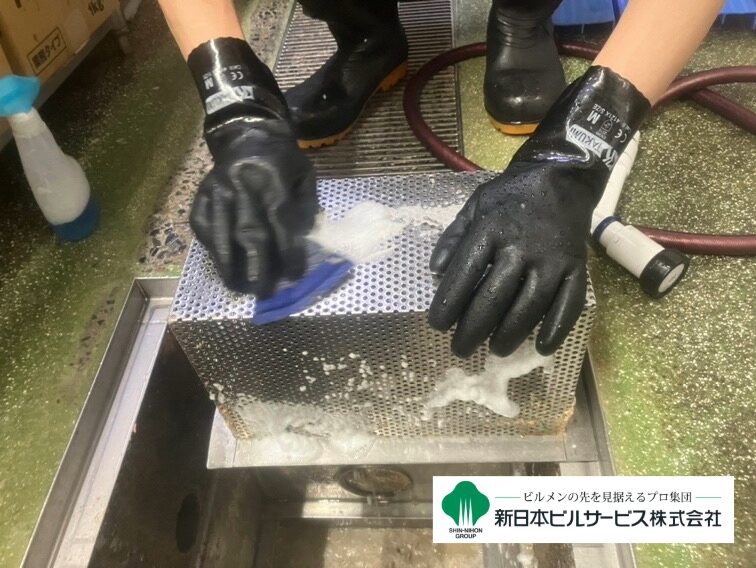 取り外したグリストラップ用バスケットを石鹸水で洗浄し、付着したゴミや油脂を除去している様子