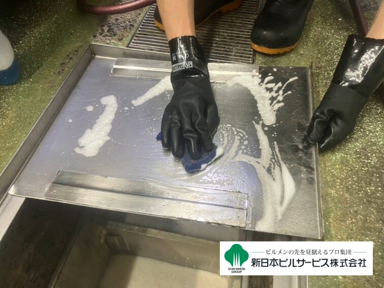 グリストラップのフタ裏に付着した油汚れを石鹸水で丁寧に洗浄している工程