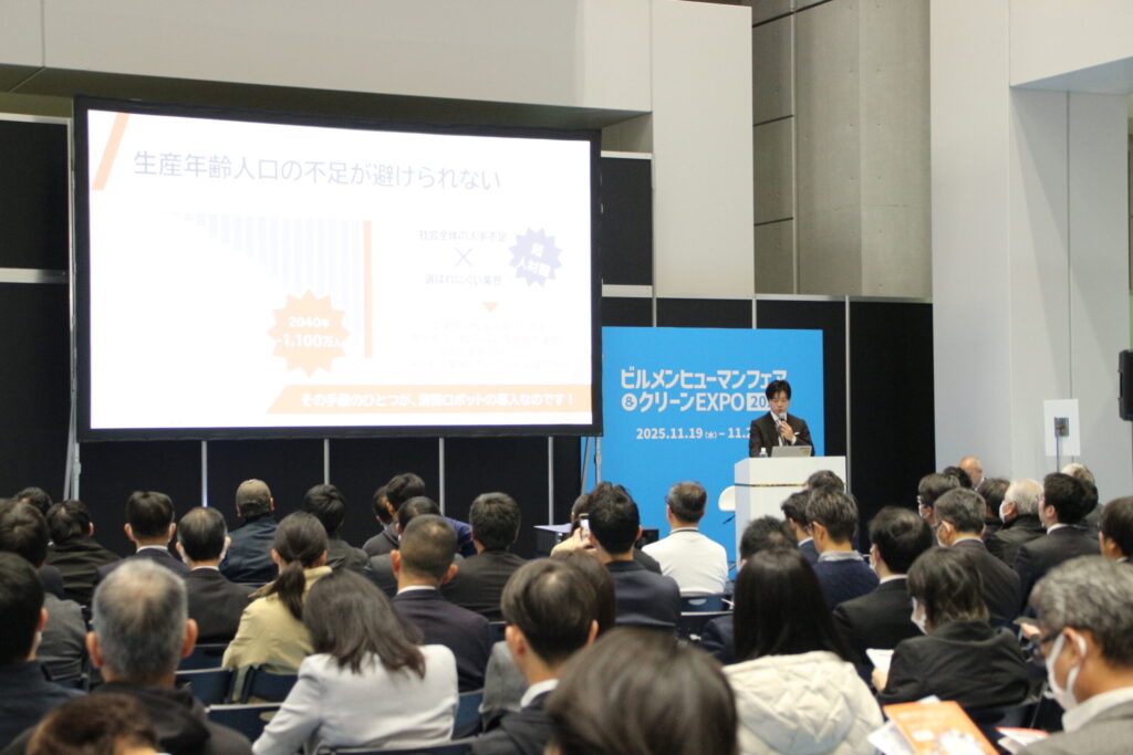 新日本ビルサービスDX推進部 取締役部長・関根陽太郎が、清掃ロボット運用の現状と展望について講演している様子