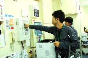 防災盤を確認しながら消防設備点検を行うスタッフ